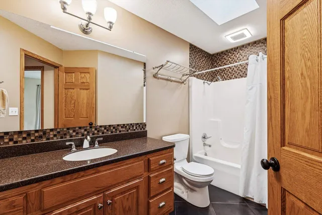 a bathroom with a granite countertop sink toilet a mirror a shower and a bathtub
