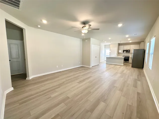 a view of a big room with wooden floor and a kitchen