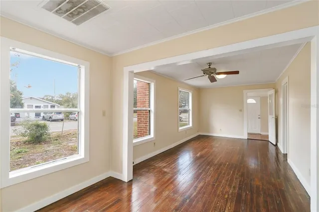 an empty room with wooden floor and windows