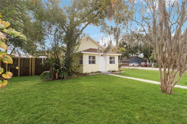 a view of a house with a big yard and large trees