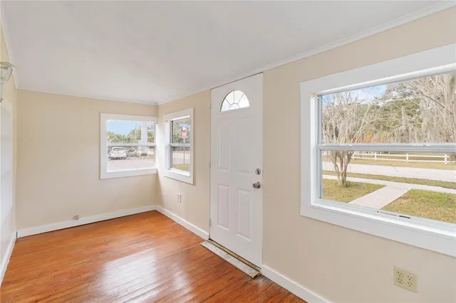 a view of an empty room with a window and wooden floor