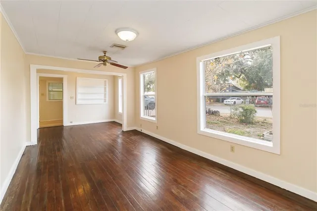an empty room with wooden floor and windows