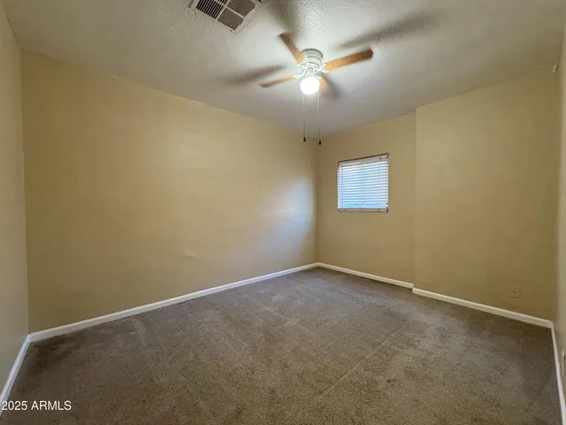 an empty room with a fan & a window