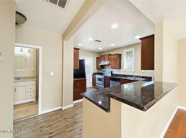 a kitchen with stainless steel appliances granite countertop a refrigerator a stove and a sink