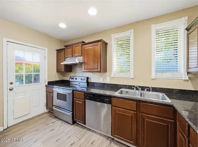 a kitchen with granite countertop a sink stove and cabinets