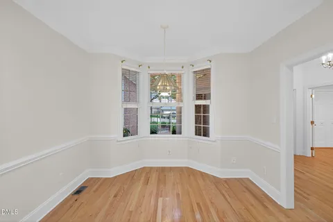 an empty room with wooden floor and a ceiling fan