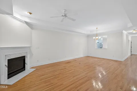 an empty room with wooden floor fireplace and chandelier