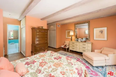 a bedroom with a bed and dresser with mirror