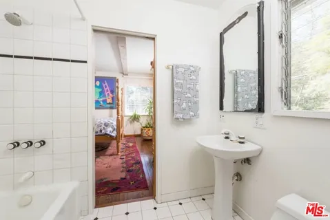 a bathroom with a sink and mirror with bathtub