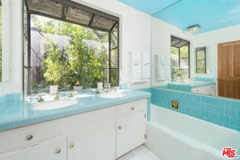 a bathroom with a granite countertop sink and a large mirror next to a window