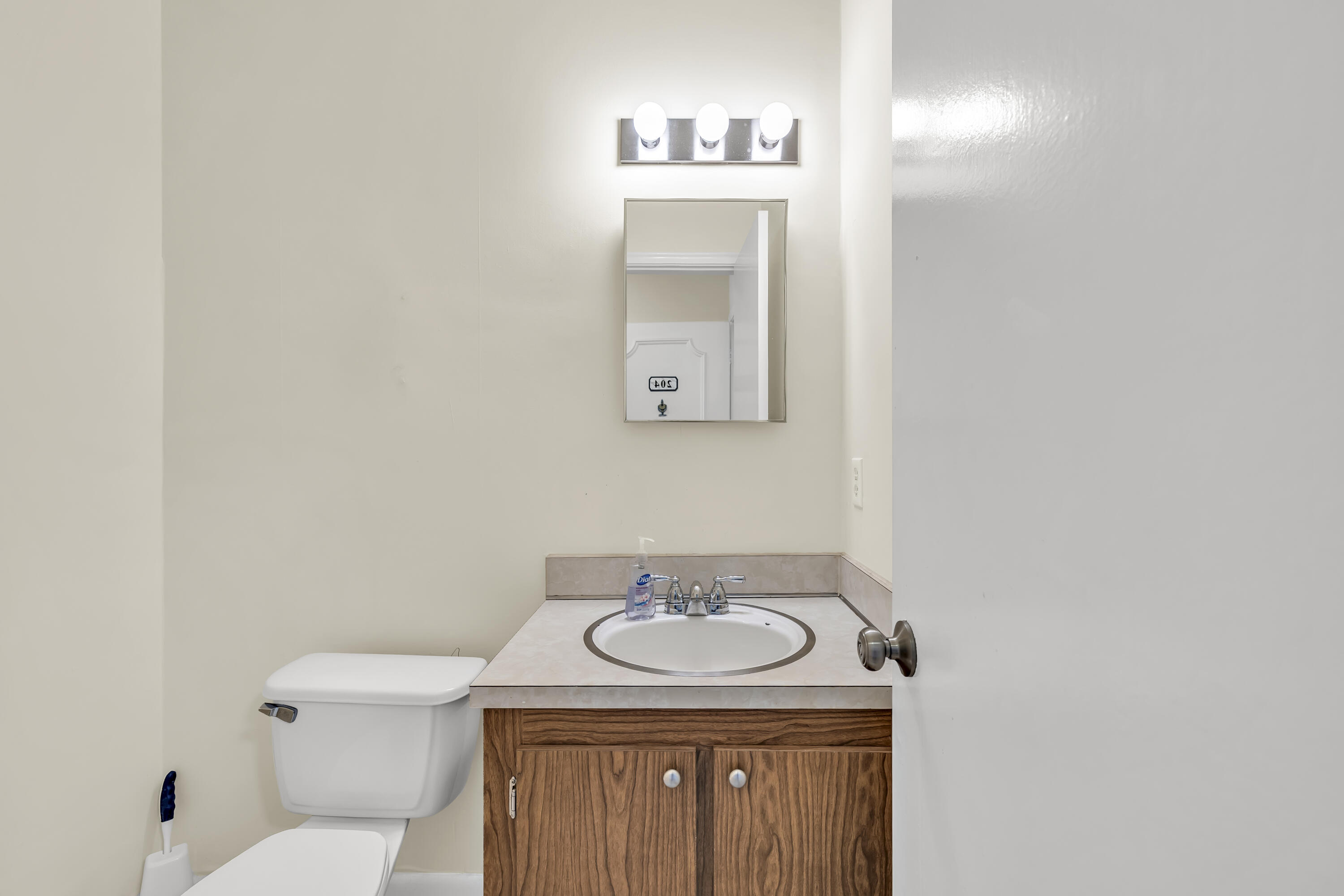298 Southwest 6th Street, Unit 204 Boca Raton, FL 33432 - Photo 20 of 22 a bathroom with a toilet sink vanity and mirror