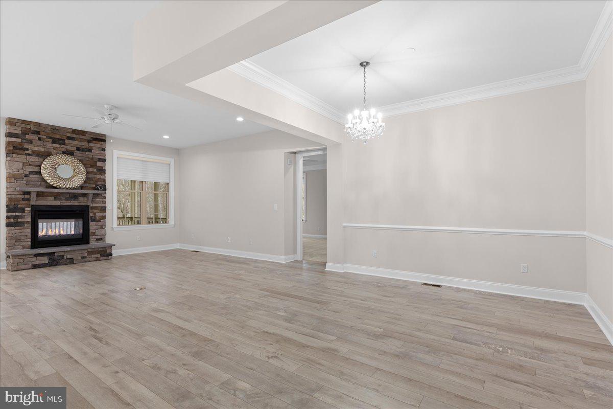 13712 Long Ridge Drive Gainesville, VA 20155 - Photo 16 of 62 an empty room with wooden floor a fireplace and chandelier