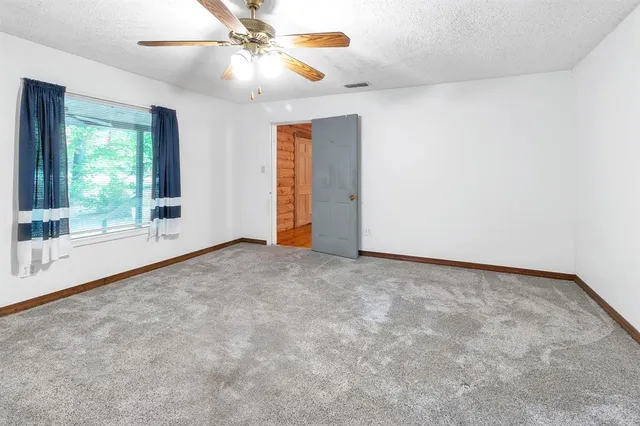 a view of an empty room with window and chandelier fan