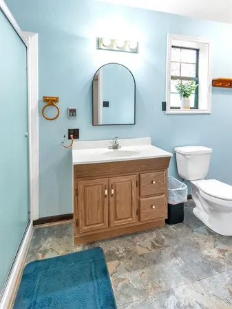 a bathroom with a granite countertop toilet sink and mirror