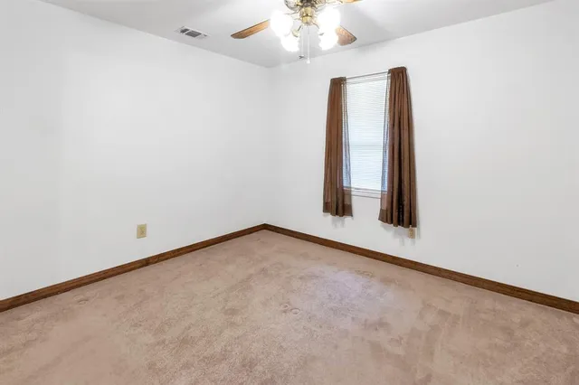 an empty room with a chandelier fan