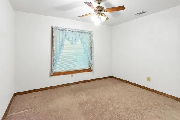 an empty room with a window and a fan