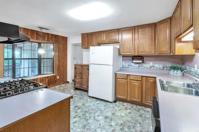 a kitchen with stainless steel appliances granite countertop a refrigerator stove a sink dishwasher and wooden cabinets with wooden floor