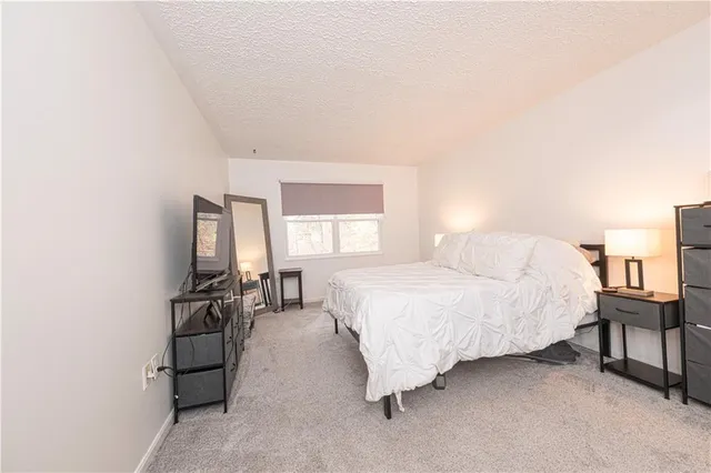 a spacious bedroom with a bed and a flat screen tv