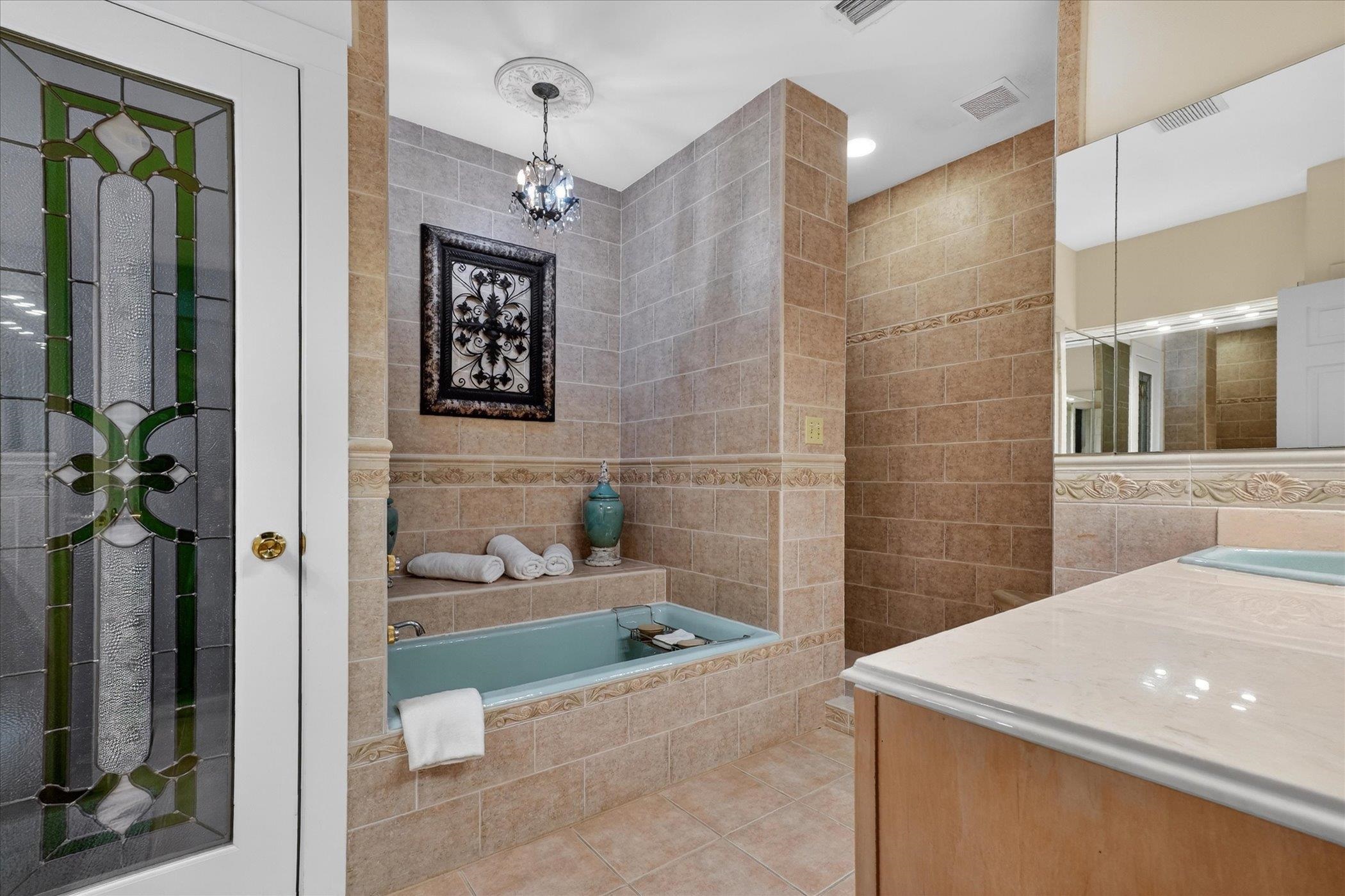 16 May Street St. Augustine, FL 32084 - Photo 53 of 85 Bathroom with tile walls, a bath, tile patterned flooring, walk in shower, and hanging lights