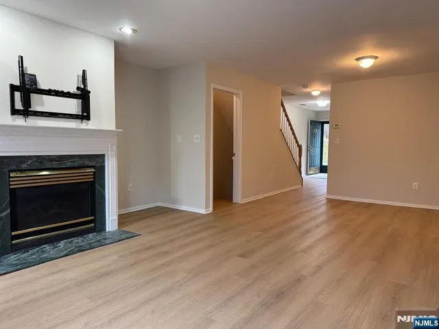a view of an empty room with wooden floor and a fireplace
