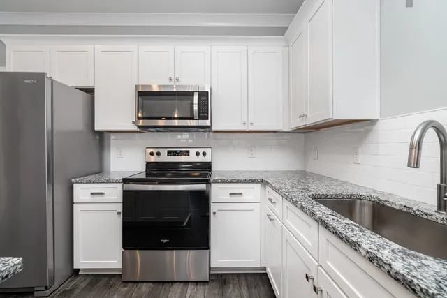 a hall with kitchen island white cabinets and wooden floor