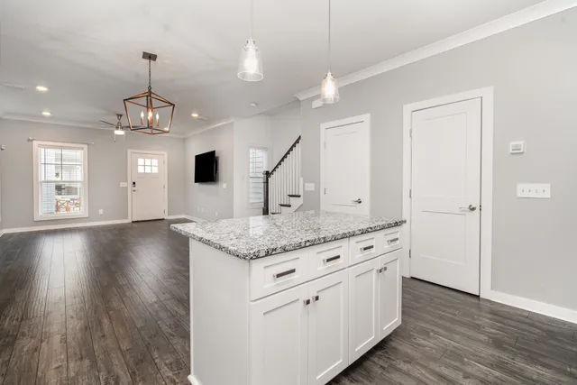 a open kitchen with white cabinets and wooden floor