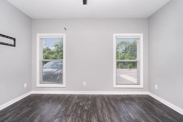 an empty room with wooden floor and windows