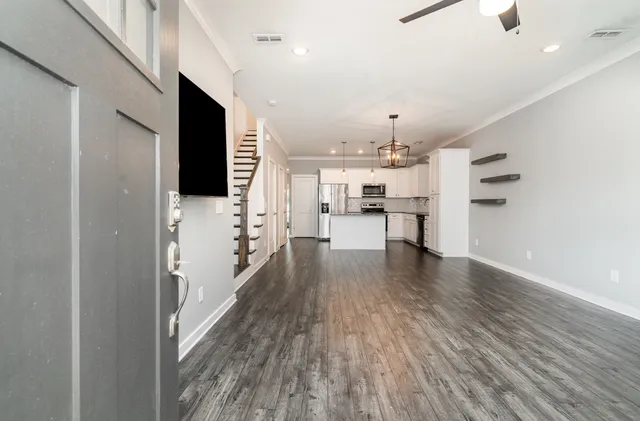 a view of a livingroom with a flat screen tv ceiling fan and wooden floor