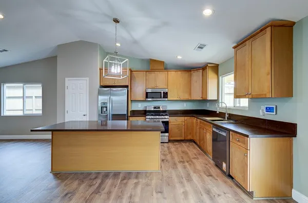 a large kitchen with cabinets wooden floor and stainless steel appliances