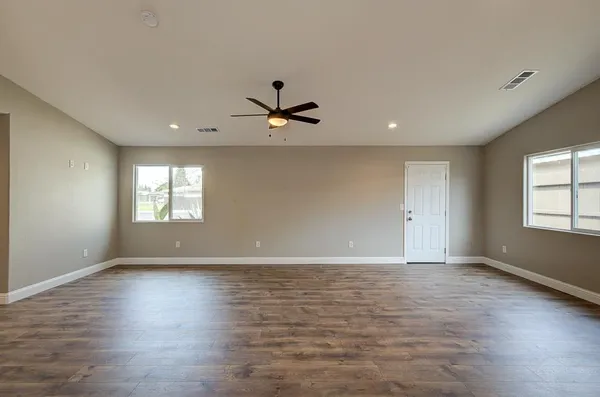 a view of an empty room with window and wooden floor
