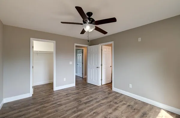 a view of empty room with wooden floor and ceiling fan