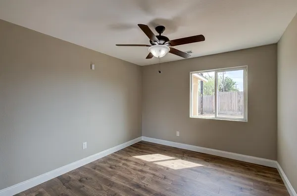 a view of empty room with wooden floor and fan