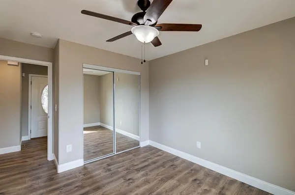 an empty room with wooden floor and a ceiling fan