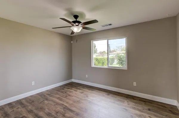 an empty room with a window and a fan