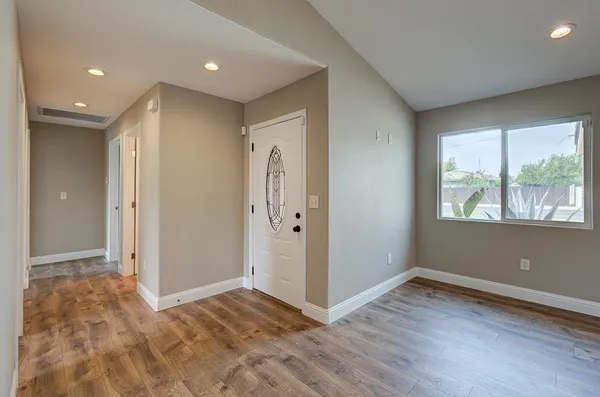 an empty room with wooden floor and windows