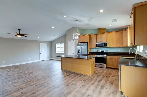 a kitchen with stainless steel appliances granite countertop wooden cabinets a stove a sink and a refrigerator