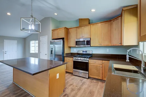 a kitchen with stainless steel appliances granite countertop a sink a stove top oven a counter space and cabinets