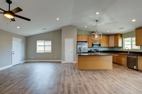 a large kitchen with stainless steel appliances granite countertop a large counter top a sink and a dishwasher
