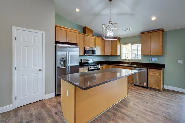 a kitchen with granite countertop a sink a counter top space stainless steel appliances and a window