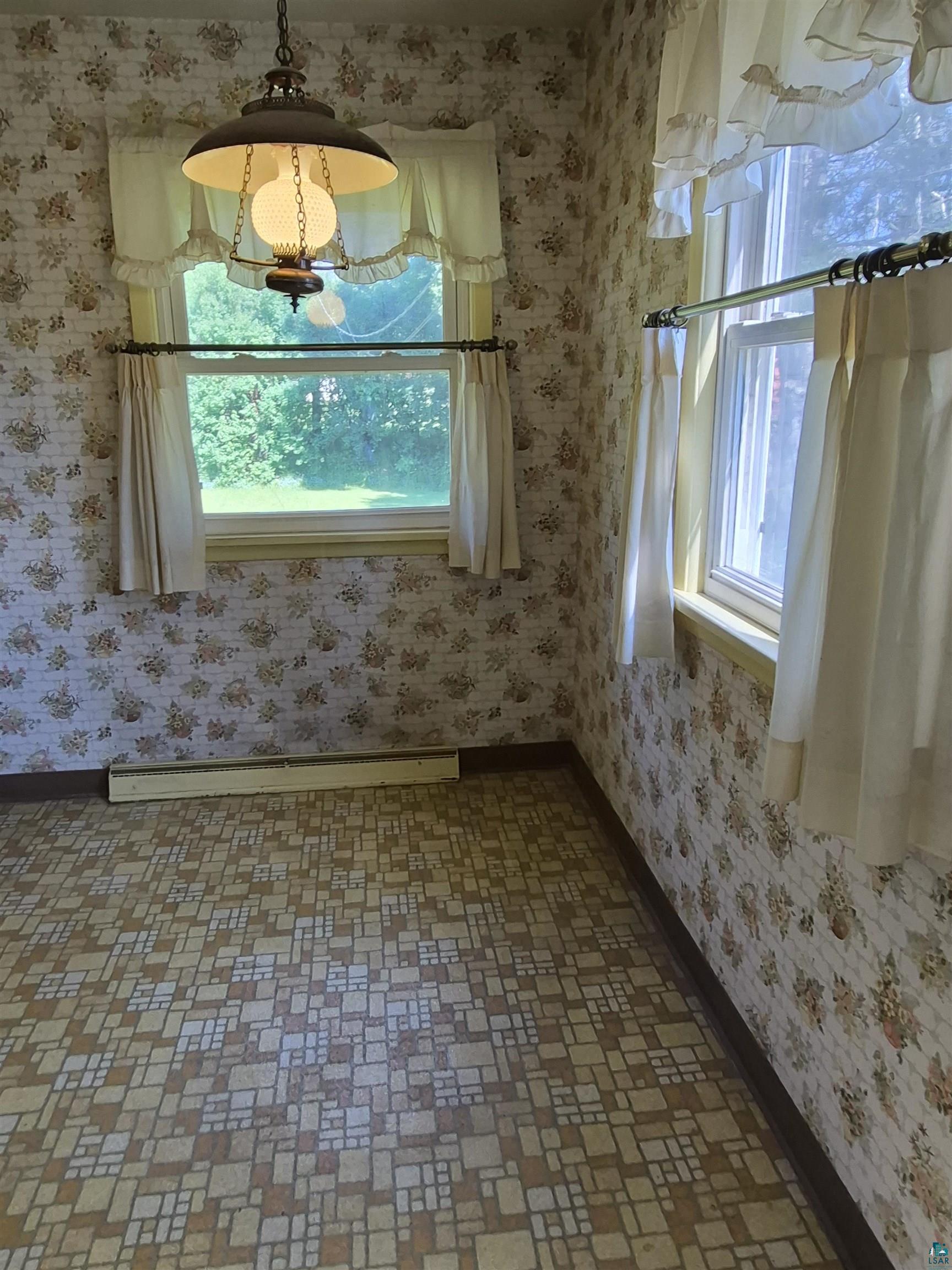 2109 West 22nd Street Duluth, MN 55811 - Photo 9 of 29 Room featuring patterned wallpaper, two windows with valances and curtains, a hanging ceiling light fixture, and tile-patterned flooring