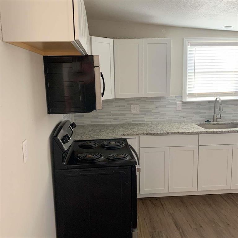 511 East Washington Street Denison, TX 75021 - Photo 3 of 12 Kitchen featuring black electric range oven, white cabinetry, stainless steel microwave, light stone counters, and a textured ceiling