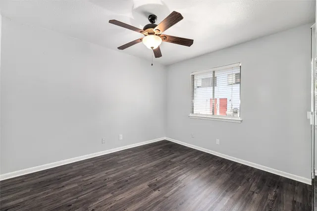 an empty room with wooden floor and ceiling fan