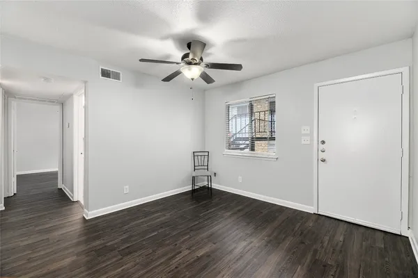 a view of empty room with wooden floor and fan