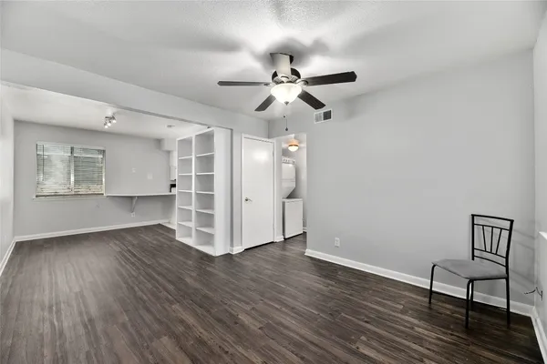 a view of empty room with wooden floor and fan