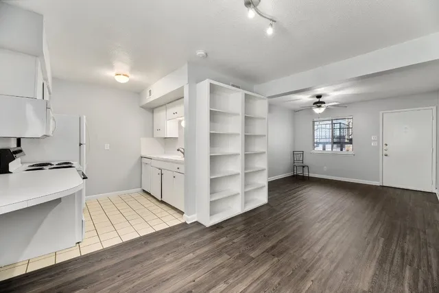 a kitchen with stainless steel appliances wooden floors and white walls