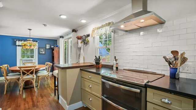 a kitchen with stainless steel appliances granite countertop a sink dishwasher and a dining table with wooden floor