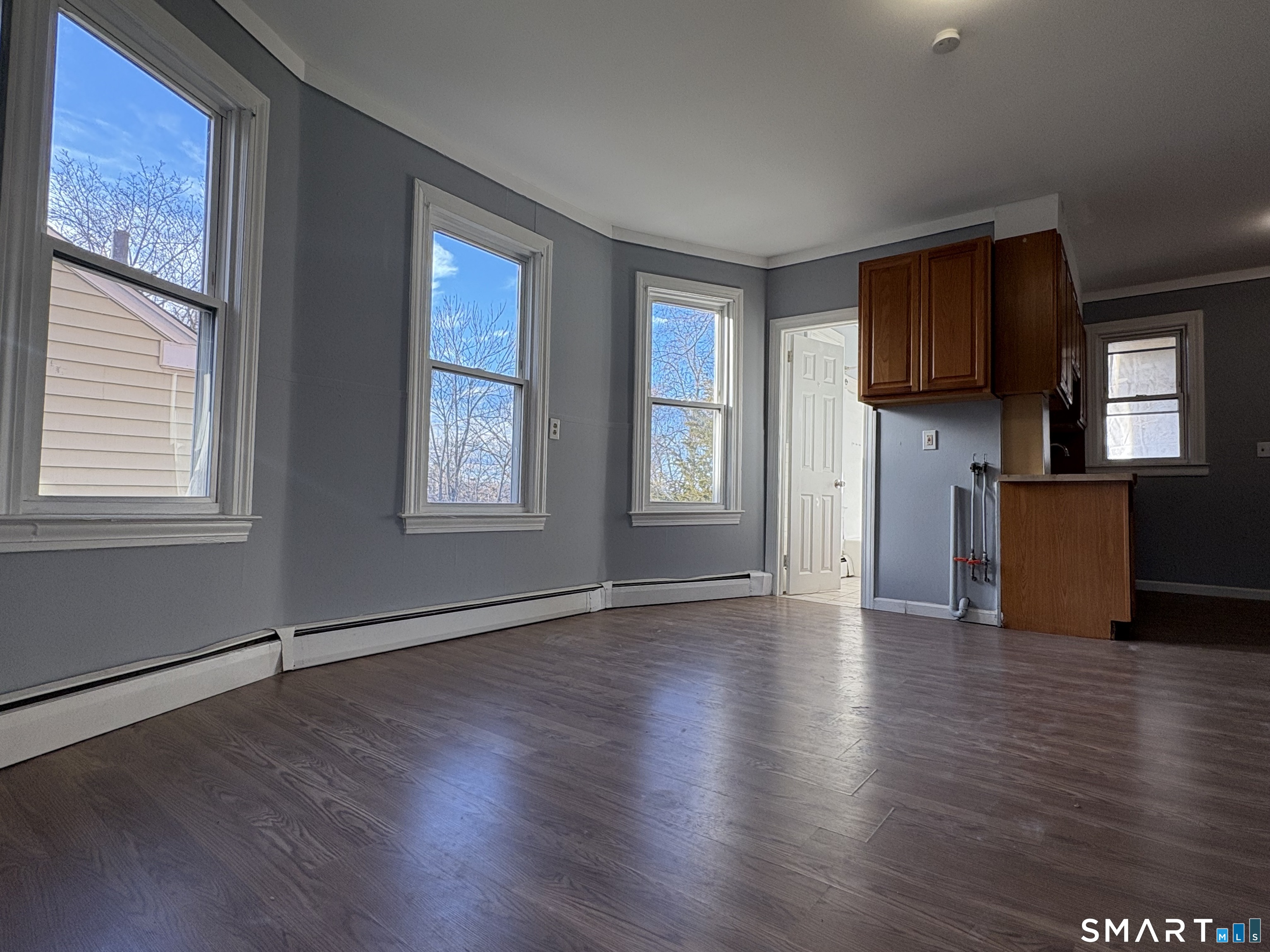 a view of an empty room with window and wooden floor