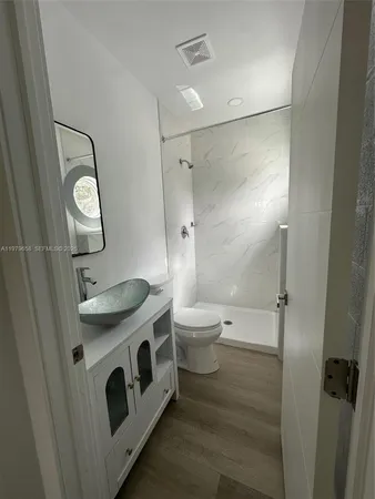 a bathroom with a granite countertop sink a toilet a mirror and shower