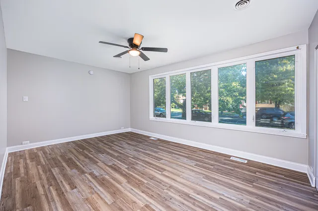 a view of empty room with wooden floor and fan