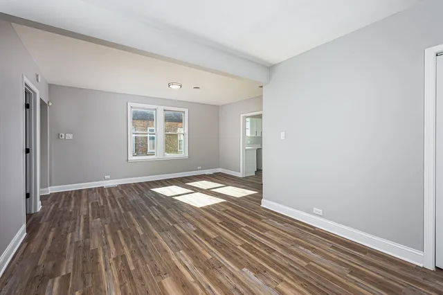 a view of empty room with wooden floor and window